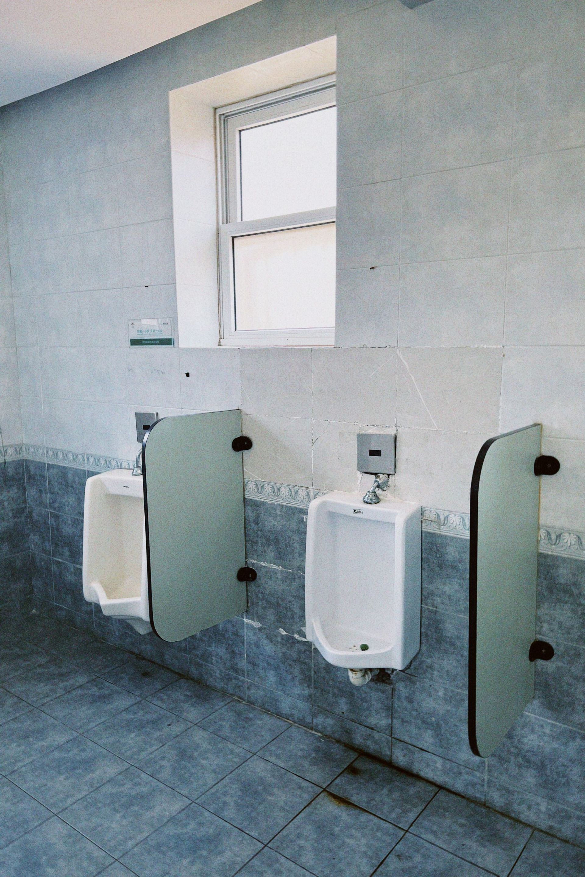 A tidy, empty public restroom featuring modern urinals and tile walls, well-lit and hygienic.